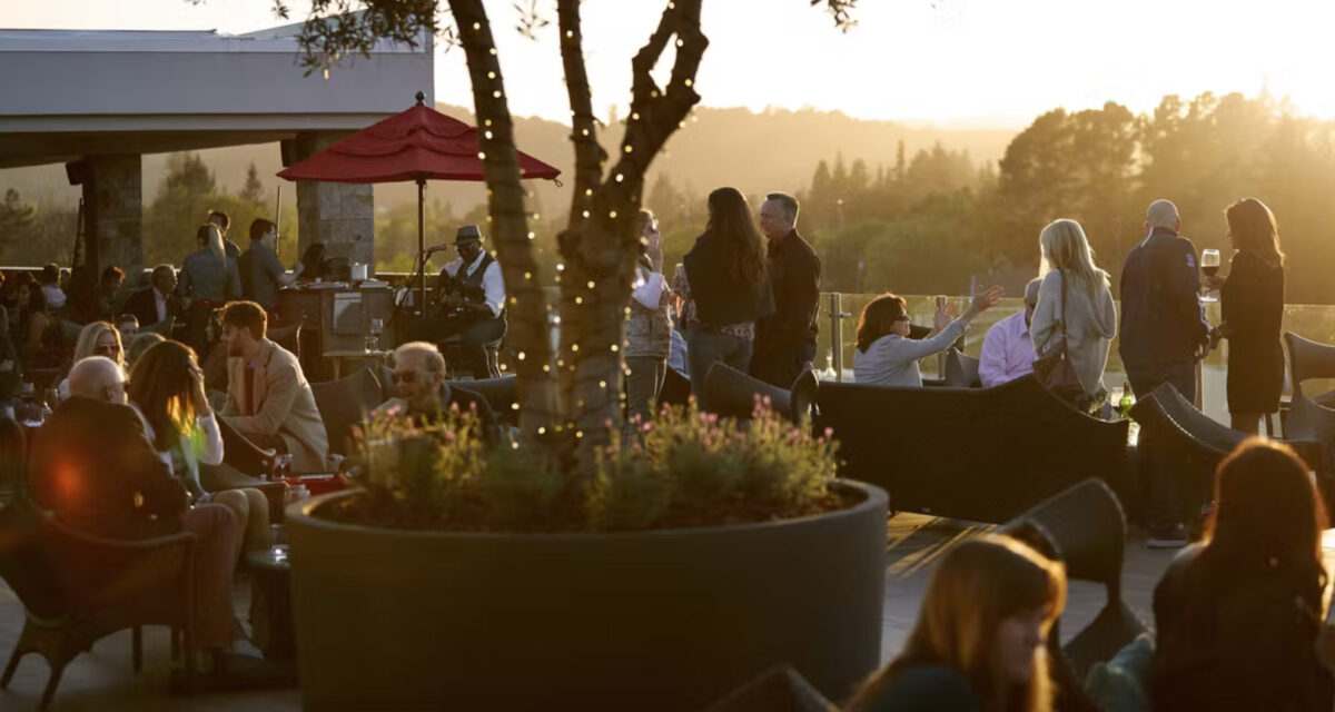 People socialize at vineyard patio in Napa with live music in background