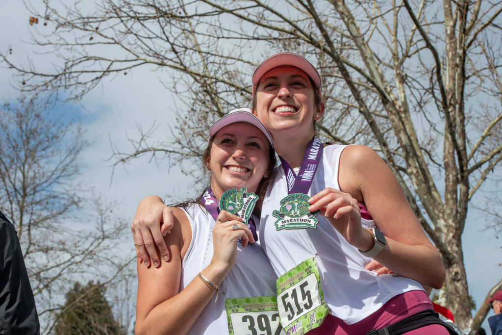 Two runners holding their Napa Valley Marathon medals after finishing the race.
