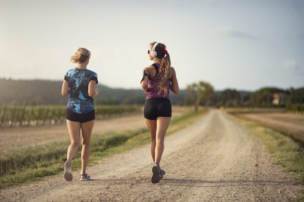 Runners jogging along a scenic vineyard road while running in Napa.